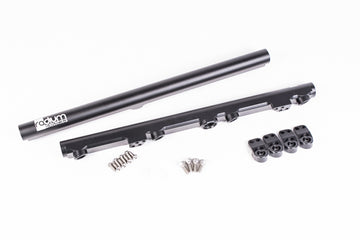 Stock photo of a black, metal Radium Fuel Rail with fittings and mounting hardware.